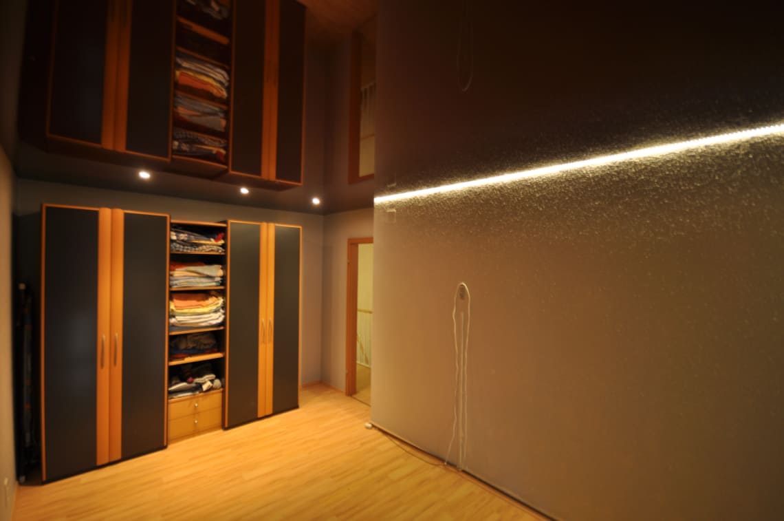 Lackspanndecke im Schlafzimmer in Bordeaux Hochglanz, Beleuchtung mit LED-Einbaustrahlern und LED-Lichtkanal in der Schattenfuge dimmbar